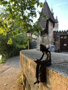 Mini Dracula statue reading a book near Vajdahunyad Castle in Budapest, adding a playful touch to the castle’s historic surroundings.