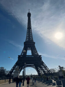 Eiffel Tower in silhouette, standing tall against a serene blue Parisian sky."