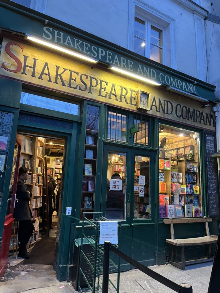 Exterior of the Shakespeare and Company bookstore in Paris, with its charming old-fashioned facade and hanging signs.