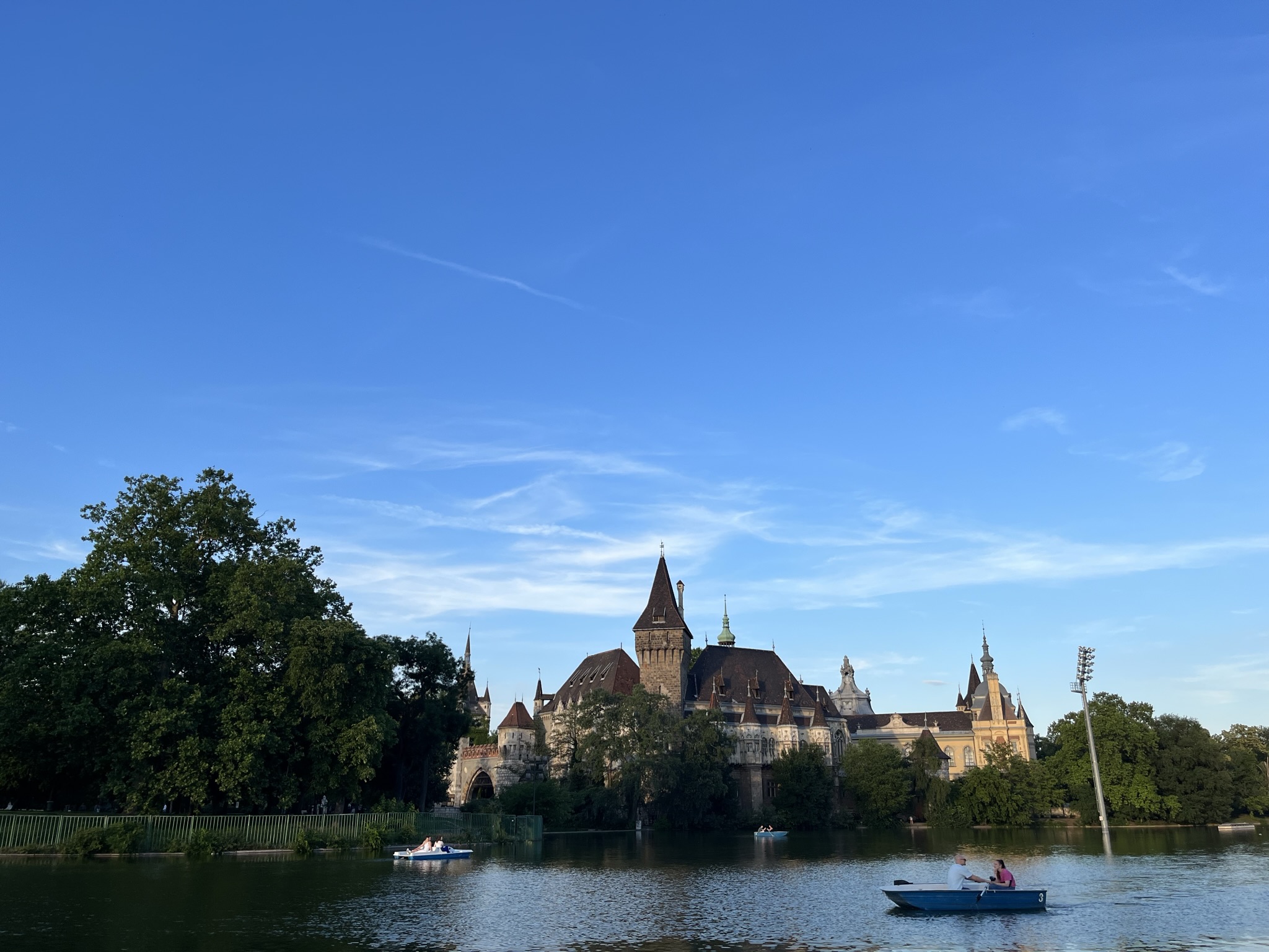Vajdahunyad Castle reflected in the river at City Park in Budapest, showcasing its mix of Gothic and Romanesque architecture surrounded by greenery.