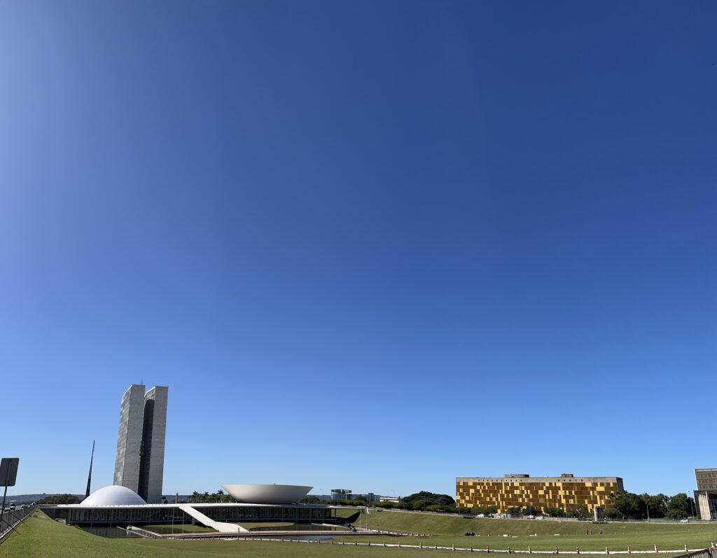 Exterior view of the Brazilian National Congress building in Brasília, featuring the iconic twin towers and dome structures under a clear sky.