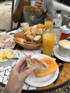 Traditional Brazilian breakfast spread with fresh bread, tropical fruits, juice, and coffee on a rustic table.